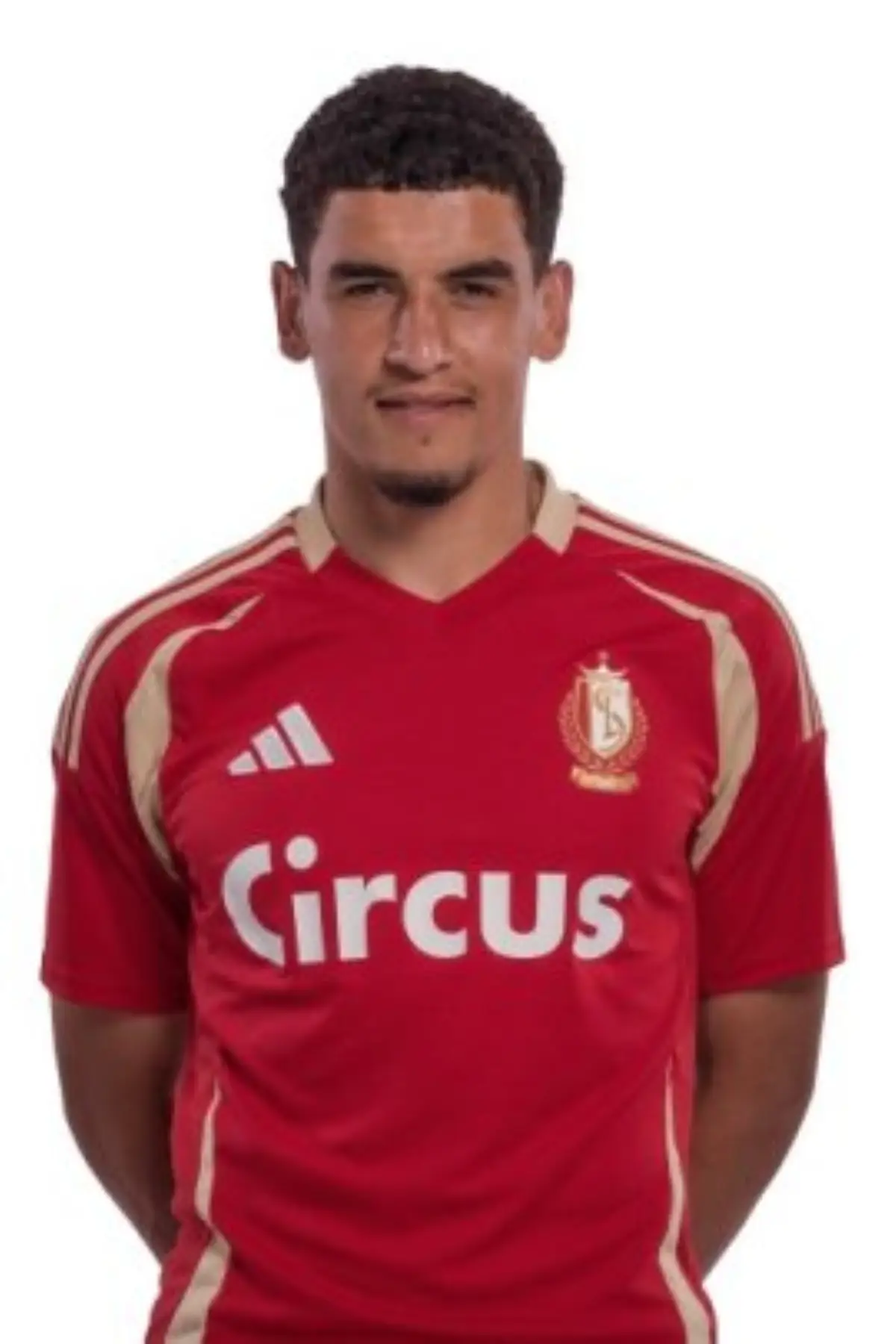 Portrait of a young man wearing a red soccer jersey with a crest on the left chest and the word 'circus' across the front. Portrait of a young man wearing a red soccer jersey with a crest on the left chest and the word 'circus' across the front.