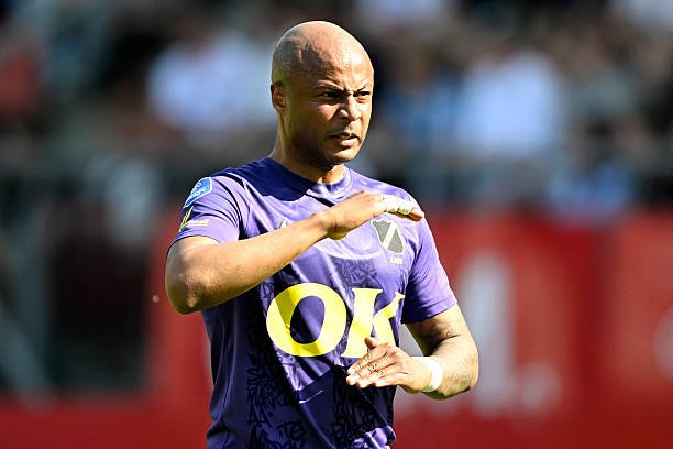 Bald rugby player in a purple jersey with 'OK' sponsor, gesturing with his arms during a match.