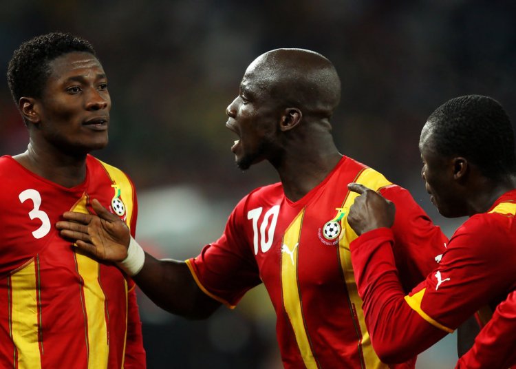 Ghana national football team players celebrate on the field in red-yellow kit, numbers 3 and 10 visible, during a match.