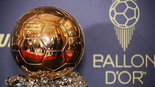 Golden Ballon d'Or trophy in a crystal base against a blue backdrop with the Ballon d'Or logo visible in the background.