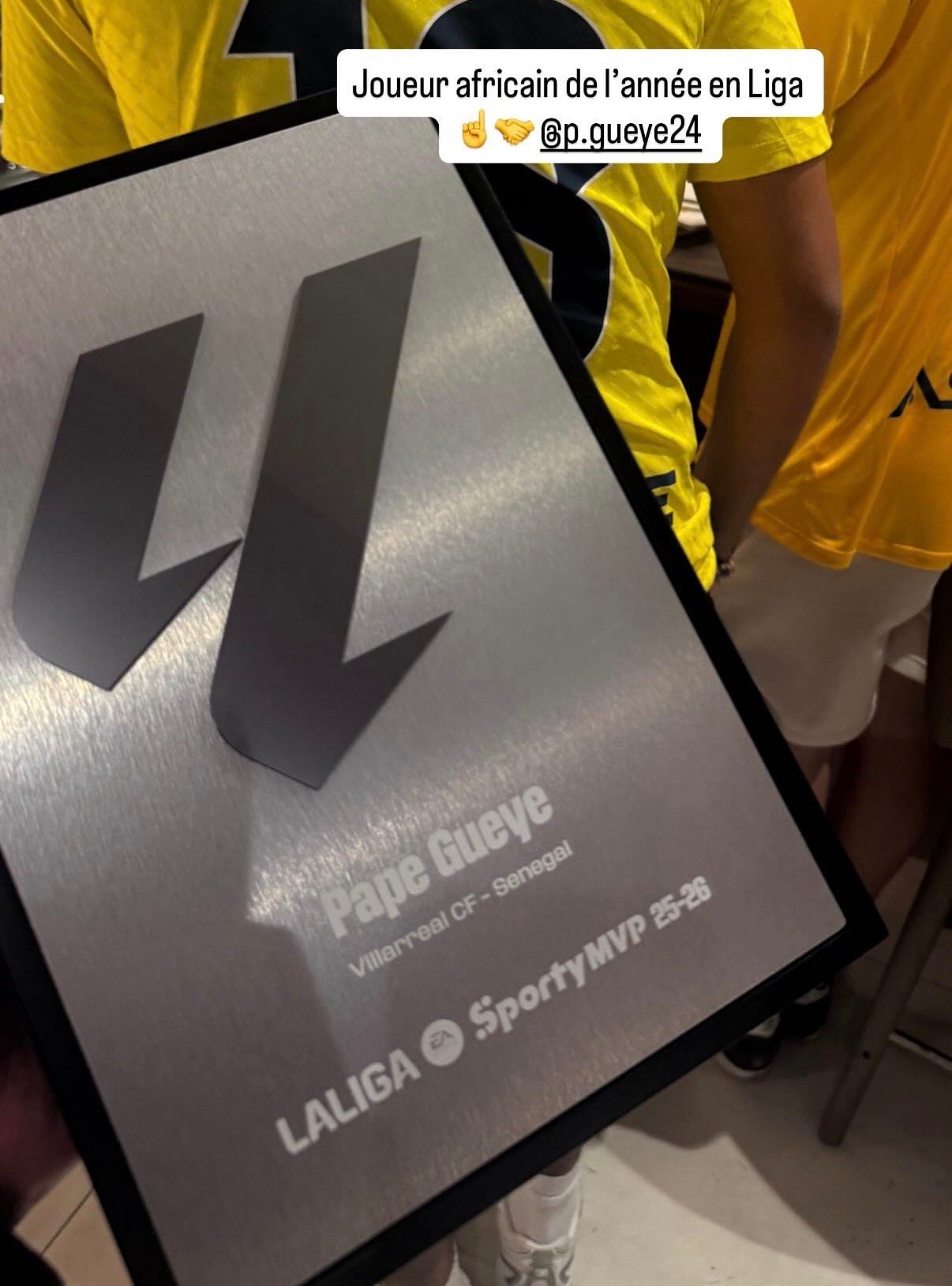 Award plaque reading 'Joueur africain de l'année en Liga' with the handle @p.gueye24, held by people in yellow jerseys.