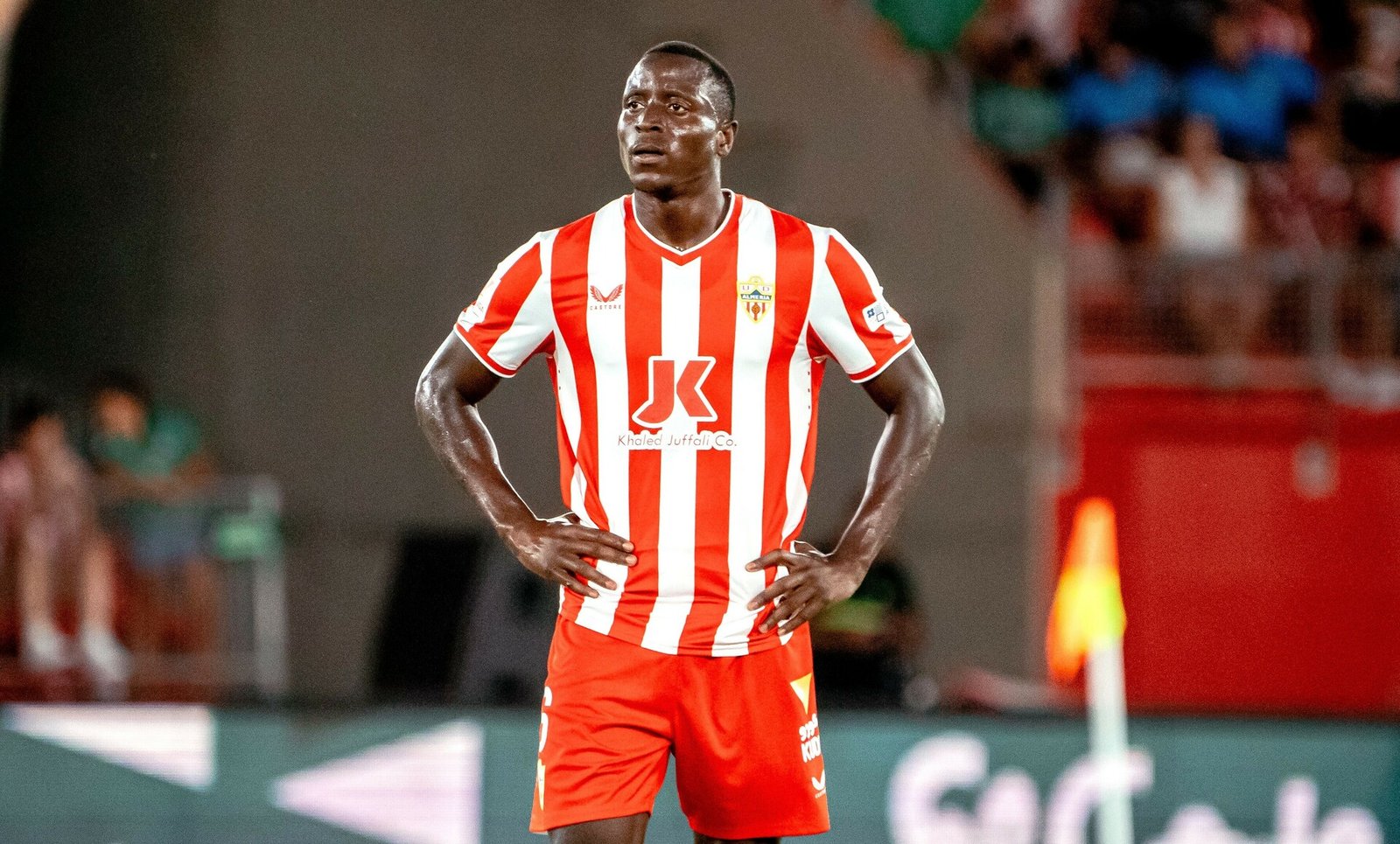 Soccer player in a red-and-white striped jersey standing with hands on hips on the field Soccer player in a red-and-white striped jersey standing with hands on hips on the field