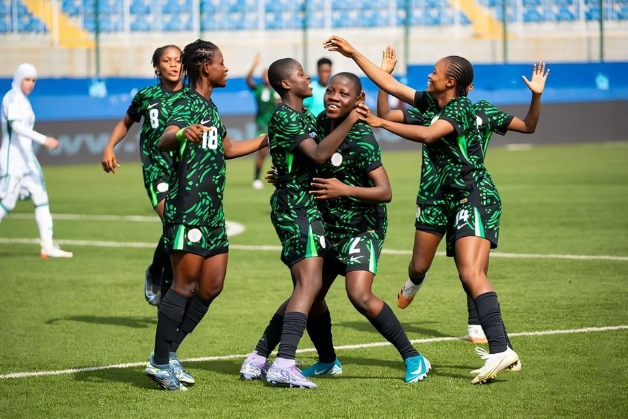 Female soccer players in green uniforms celebrate together on a sunny pitch, arms raised in triumph with stadium seating in the background. Female soccer players in green uniforms celebrate together on a sunny pitch, arms raised in triumph with stadium seating in the background.