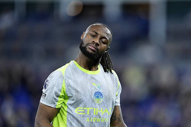 Soccer player in gray neon-trimmed training kit with Etihad Airways logo, eyes closed and head tilted to the side on the field, suggesting fatigue or focus. Soccer player in gray neon-trimmed training kit with Etihad Airways logo, eyes closed and head tilted to the side on the field, suggesting fatigue or focus.