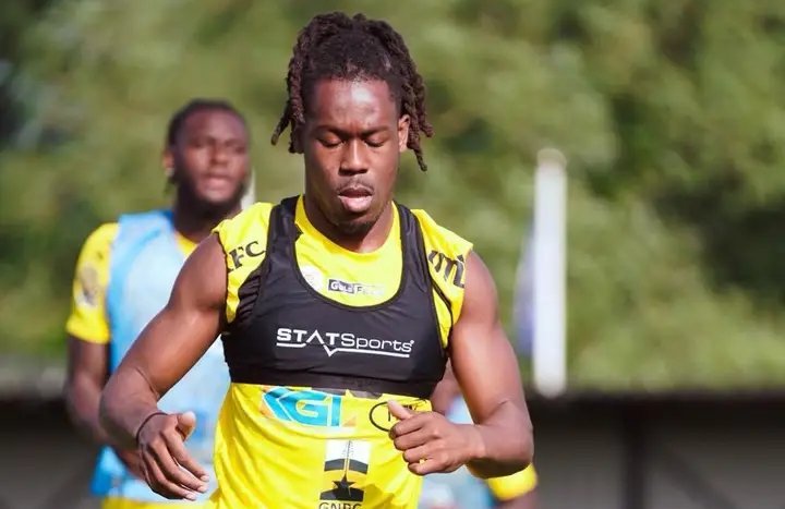 Male sprinter in a yellow and black training vest running during practice, focused on the pace. Male sprinter in a yellow and black training vest running during practice, focused on the pace.
