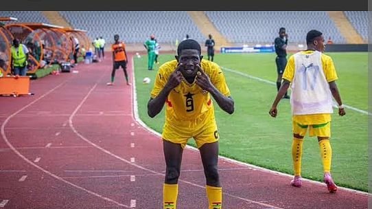 Soccer player in a yellow jersey bends forward on the track near the sideline, teammates in yellow nearby in a stadium setting.