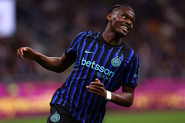 Inter Milan player in a blue-and-black striped jersey celebrating with a smile on the pitch, Betsson sponsor visible on the jersey. Inter Milan player in a blue-and-black striped jersey celebrating with a smile on the pitch, Betsson sponsor visible on the jersey.