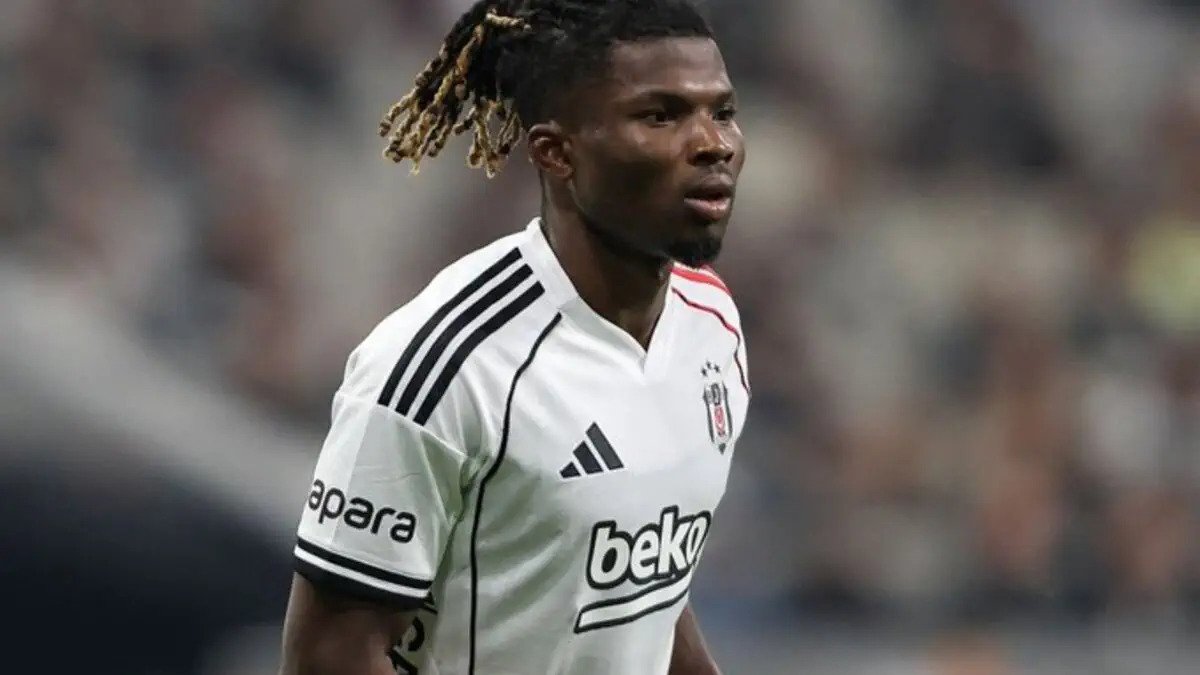 Footballer with blond-dreadlock hairstyle in a white Beşiktaş jersey on the soccer field, focused in play.