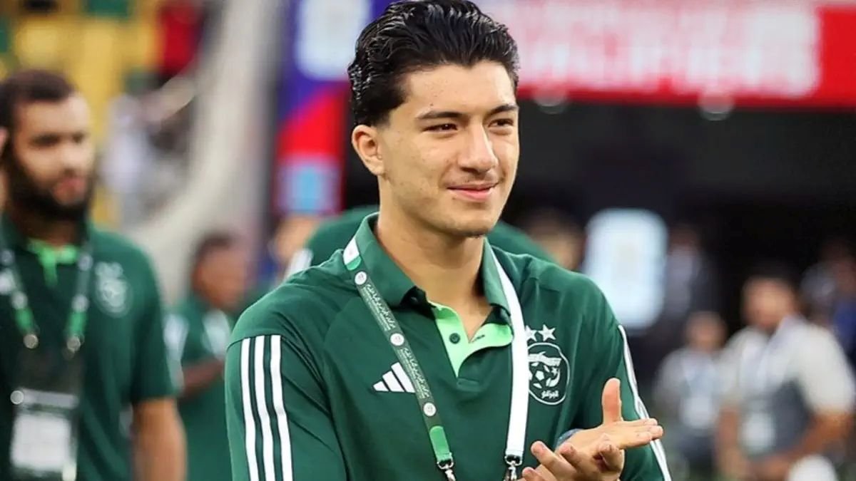 Young man in a green sports polo with a lanyard, clapping at an event stadium Young man in a green sports polo with a lanyard, clapping at an event stadium