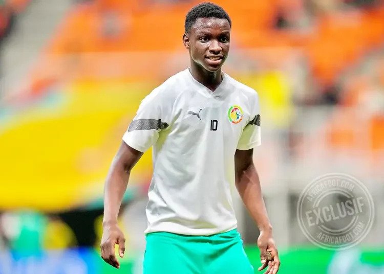 Soccer player in a white training shirt with number 10 and turquoise shorts on a stadium pitch.