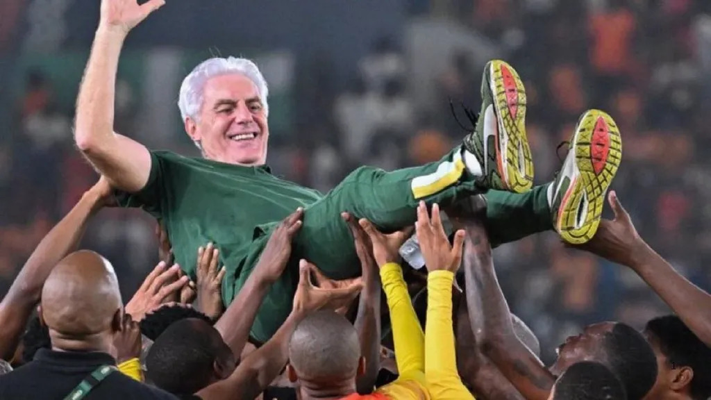 Older man in a green outfit being lifted and carried over a cheering crowd at a stadium. Older man in a green outfit being lifted and carried over a cheering crowd at a stadium.