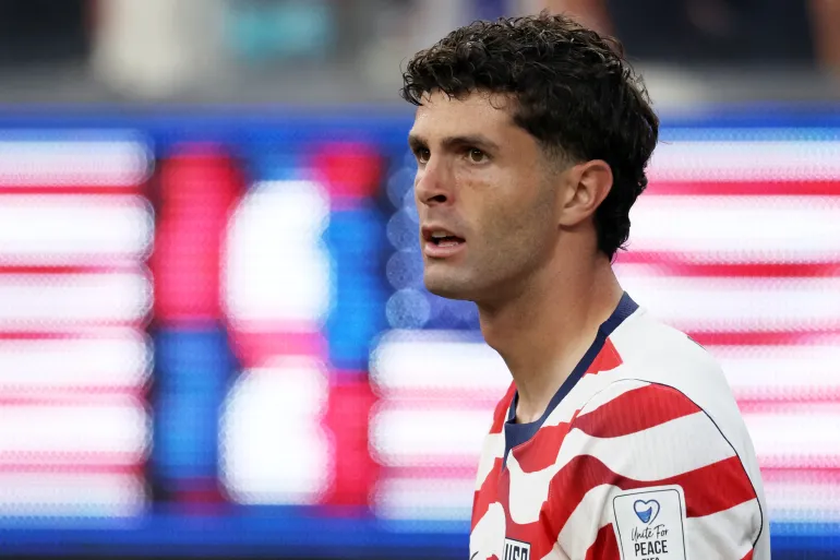 Male soccer player in a red-and-white striped USA jersey looking to the right on the field, during a match. Male soccer player in a red-and-white striped USA jersey looking to the right on the field, during a match.