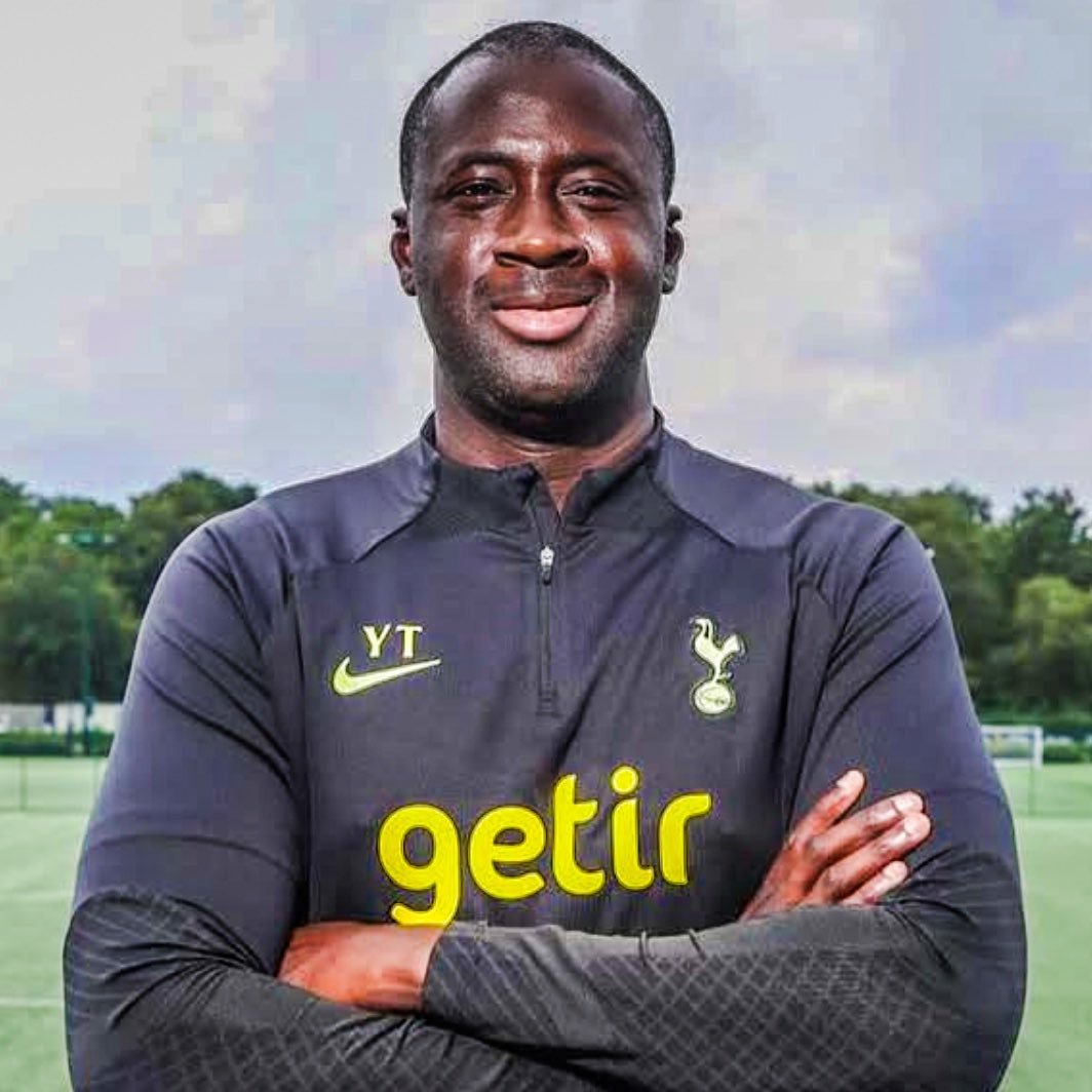 Professional football player standing on a training field with arms crossed, wearing a dark Tottenham training top and the Getir sponsor logo.
