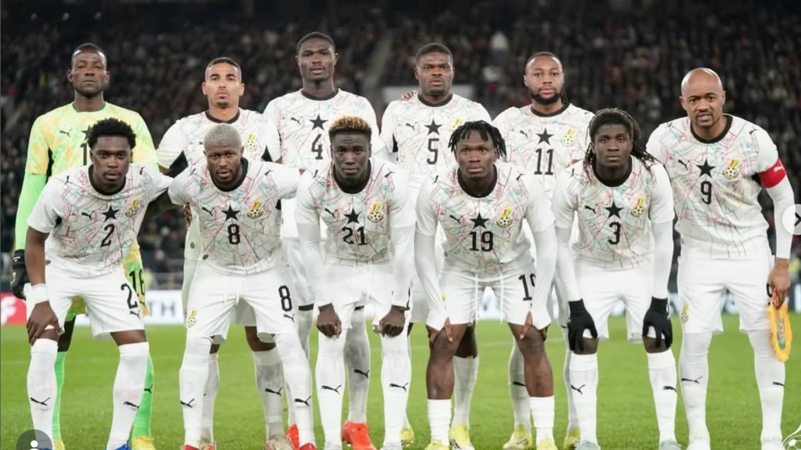 Ghana national football team players pose for a group photo on the pitch, wearing white kits with black stars. Ghana national football team players pose for a group photo on the pitch, wearing white kits with black stars.