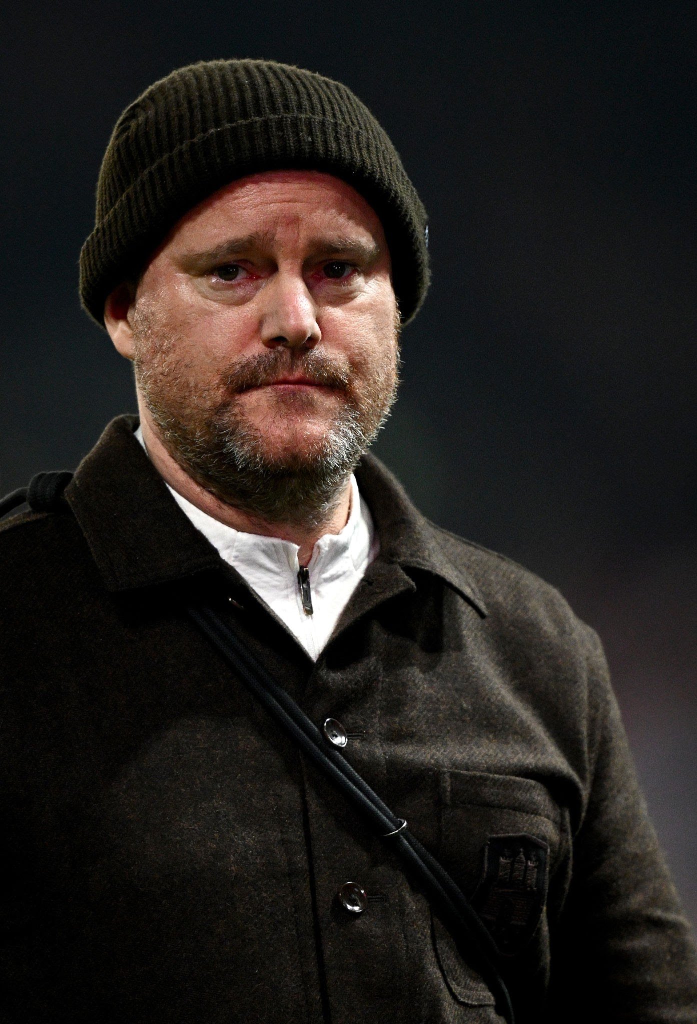 Close-up of a man in a dark knit beanie and brown wool coat, looking at the camera. Close-up of a man in a dark knit beanie and brown wool coat, looking at the camera.