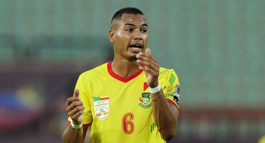 Male soccer player in a yellow jersey with the number 6 gesturing while talking on the field during a match