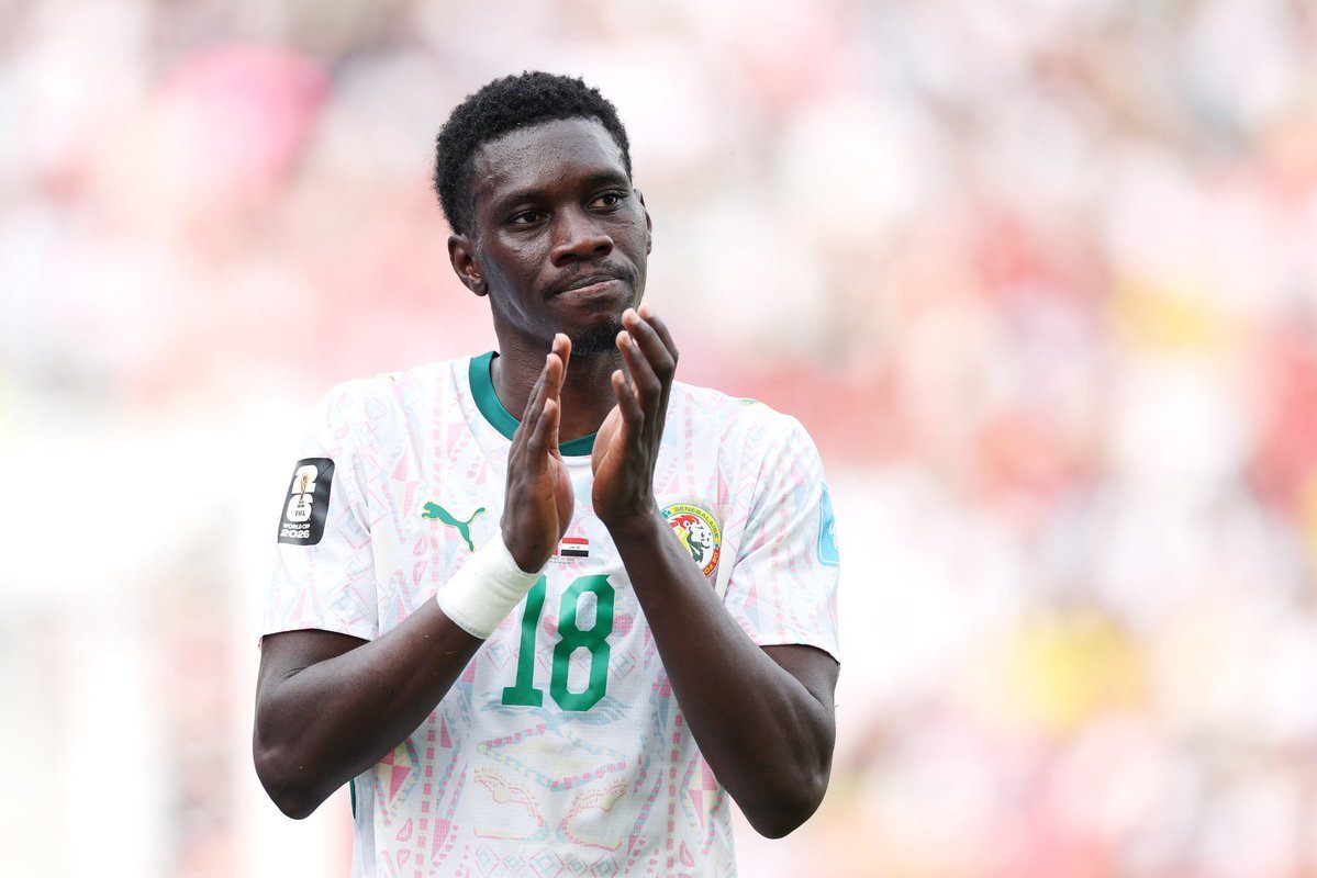 Soccer player in a Senegal jersey with number 18 clapping on a field, stadium blurred in background Soccer player in a Senegal jersey with number 18 clapping on a field, stadium blurred in background