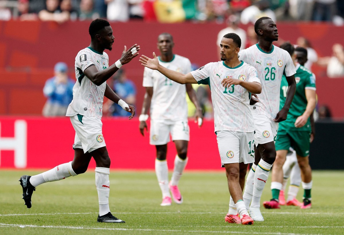 Members of the Senegal national football team celebrate on the field, high-fiving each other in white jerseys with green accents. Members of the Senegal national football team celebrate on the field, high-fiving each other in white jerseys with green accents.