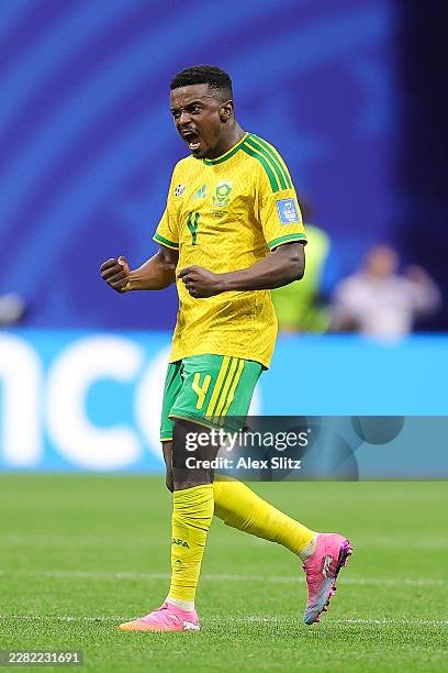 South African soccer player in a yellow kit celebrating on the grass field with pink cleats. South African soccer player in a yellow kit celebrating on the grass field with pink cleats.