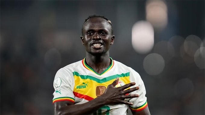 Ghanaian footballer in a white national team jersey places his hand over his heart on the field during a match. Ghanaian footballer in a white national team jersey places his hand over his heart on the field during a match.