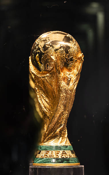 Gold FIFA World Cup trophy on a dark background, close-up of the globe and figures at the top Gold FIFA World Cup trophy on a dark background, close-up of the globe and figures at the top