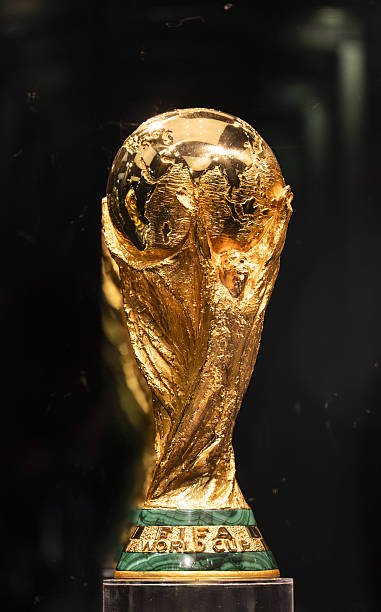 Golden FIFA World Cup trophy close-up showing globe and twisted figures on a green band base.