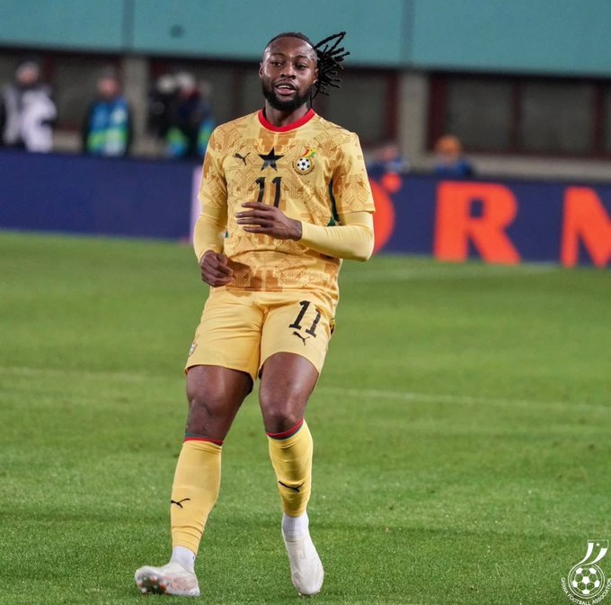 Soccer player in yellow kit with number 11 dribbling on a green field during a match, crest visible on chest and stars near collar area.