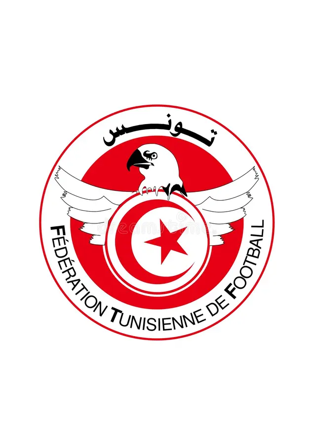 Circular logo of the Tunisian Football Federation featuring a white eagle over a red crescent and star with surrounding text. Circular logo of the Tunisian Football Federation featuring a white eagle over a red crescent and star with surrounding text.