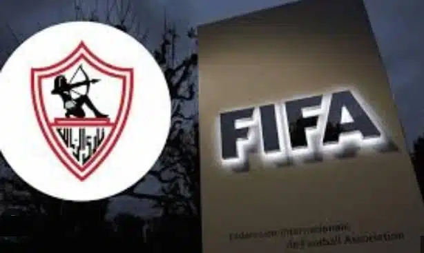 Two logos side by side: left is a circular white badge with a red shield and archer emblem, right shows a vertical sign with the word FIFA in bold letters. Two logos side by side: left is a circular white badge with a red shield and archer emblem, right shows a vertical sign with the word FIFA in bold letters.