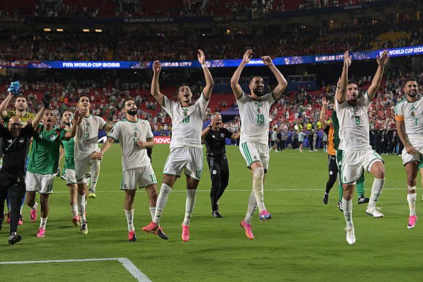 Soccer players in white and green uniforms celebrate on the field with arms raised as fans cheer in the stands, after a match at the stadium. Soccer players in white and green uniforms celebrate on the field with arms raised as fans cheer in the stands, after a match at the stadium.