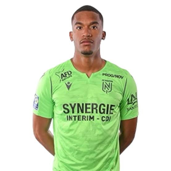 Male soccer player in a bright green jersey facing the camera, sponsor text 'SYNERGIE INTERIM – CDI' visible with team crest on chest. Male soccer player in a bright green jersey facing the camera, sponsor text 'SYNERGIE INTERIM – CDI' visible with team crest on chest.