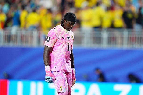 Soccer goalkeeper in a pink kit and gloves looking down on the field during a match. Soccer goalkeeper in a pink kit and gloves looking down on the field during a match.