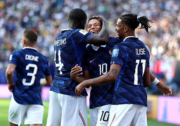 French national team players celebrate a goal—group hug on the pitch in blue kits.] , French national team players celebrate a goal—group hug on the pitch in blue kits.] ,