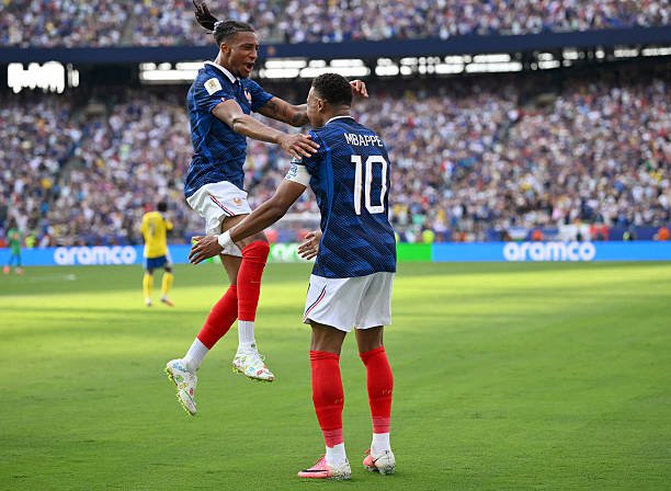 Two soccer players in blue jerseys celebrate a goal on the green pitch as the crowd cheers in the stands, one leaping toward the other. Two soccer players in blue jerseys celebrate a goal on the green pitch as the crowd cheers in the stands, one leaping toward the other.