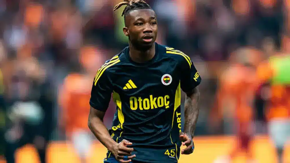 Soccer player in a dark blue jersey with yellow accents running on the field, Otokoc sponsor logo visible on chest.