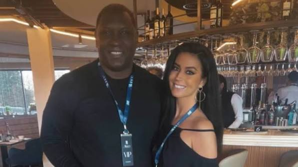 Smiling man and woman posing together at a stylish bar, both wearing blue VIP lanyards. Smiling man and woman posing together at a stylish bar, both wearing blue VIP lanyards.