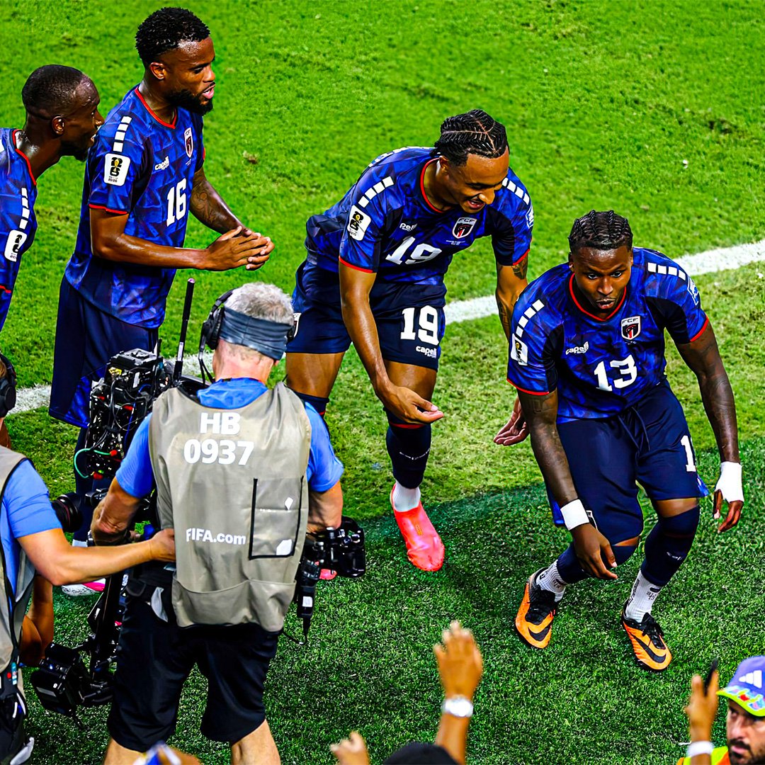 Soccer players in blue uniforms celebrate a moment on the green field with a cameraman filming nearby. Soccer players in blue uniforms celebrate a moment on the green field with a cameraman filming nearby.