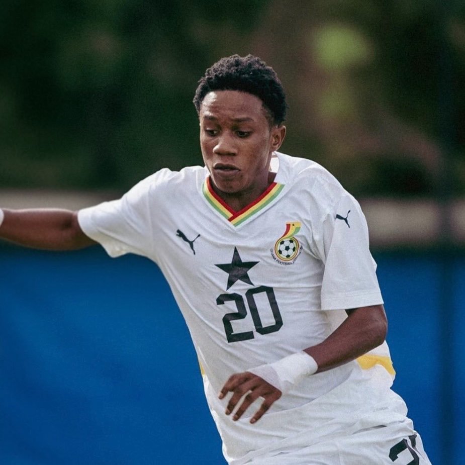 Soccer player in a white jersey with number 20, sprinting on the field; Ghana crest on chest. Soccer player in a white jersey with number 20, sprinting on the field; Ghana crest on chest.