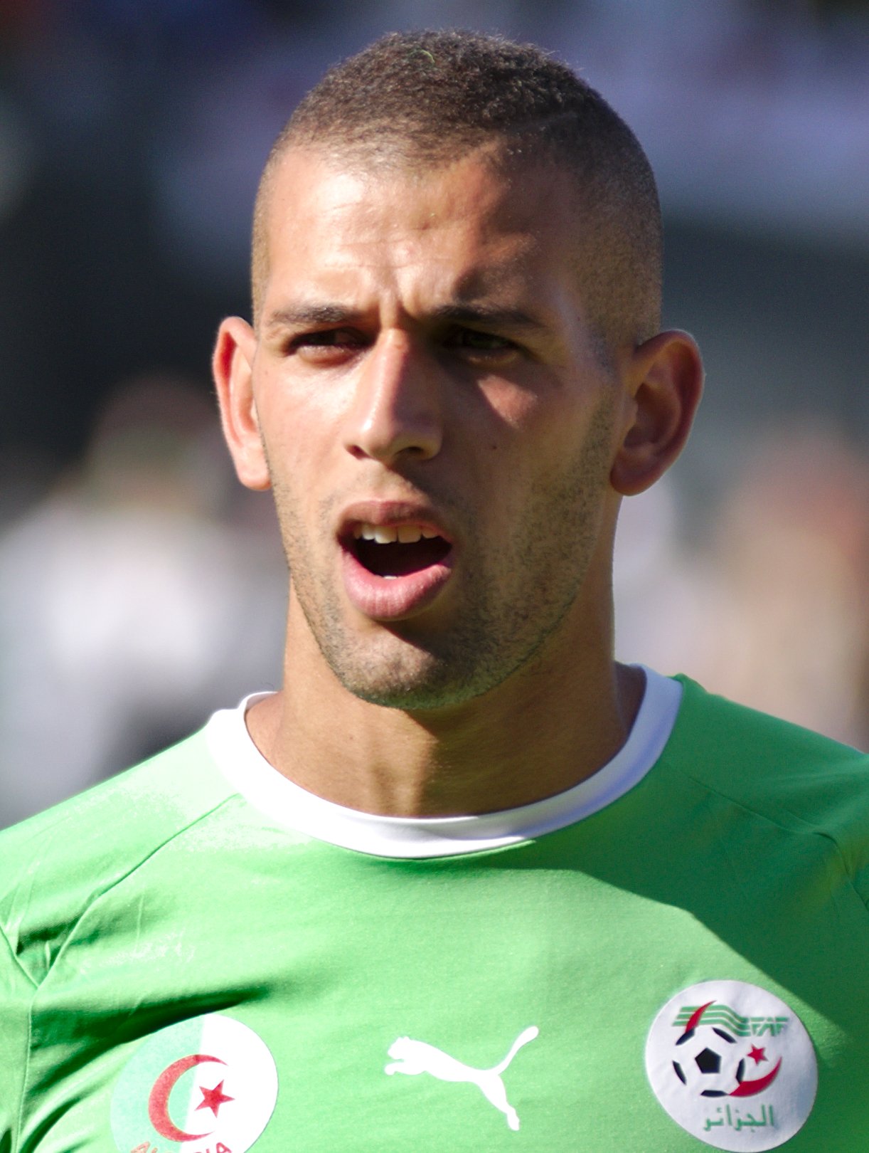 Close-up of a male soccer player in a green jersey, mouth open as if he’s speaking or about to kick. Close-up of a male soccer player in a green jersey, mouth open as if he’s speaking or about to kick.