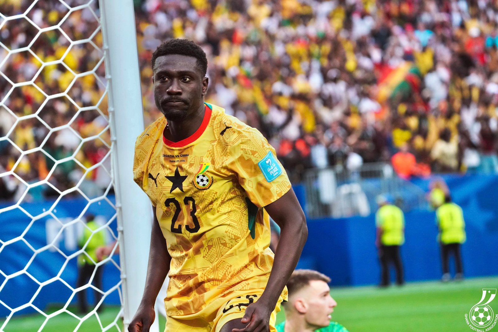 Soccer player in a yellow jersey with number 23 near the goal net during a match, stands filled with colorful spectators in the background. Soccer player in a yellow jersey with number 23 near the goal net during a match, stands filled with colorful spectators in the background.