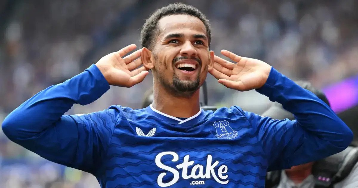 Soccer player in a blue jersey celebrating with hands cupped to ears, smiling toward the crowd. Soccer player in a blue jersey celebrating with hands cupped to ears, smiling toward the crowd.