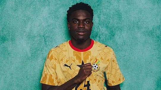 Portrait of a male soccer player in a yellow jersey with a crest and number 4, standing against a teal background, with one hand near his chest. Portrait of a male soccer player in a yellow jersey with a crest and number 4, standing against a teal background, with one hand near his chest.