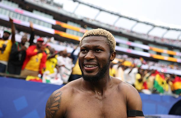 Smiling shirtless male athlete with blond hair after a race, crowd cheering in the stadium behind him. Smiling shirtless male athlete with blond hair after a race, crowd cheering in the stadium behind him.