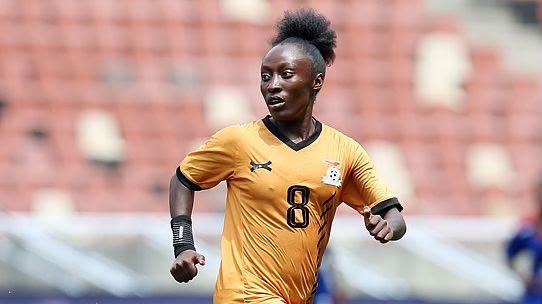 Female soccer player in an orange kit with the number 8, mid-stride on the field. Female soccer player in an orange kit with the number 8, mid-stride on the field.