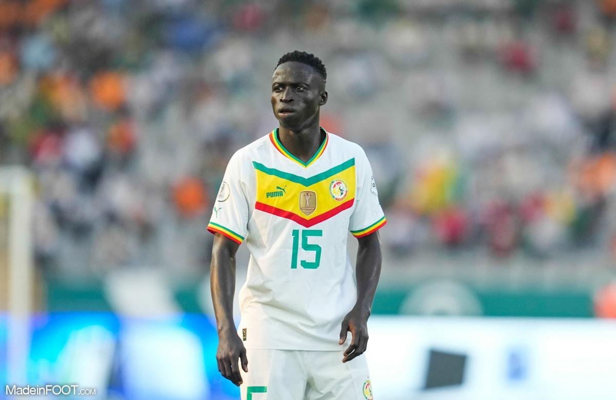 Soccer player in a white Senegal jersey #15 standing on the field during a match.