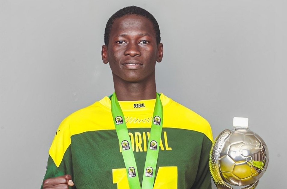 Young male athlete in a yellow-green jersey wearing a green medal around his neck and holding a trophy, facing the camera.