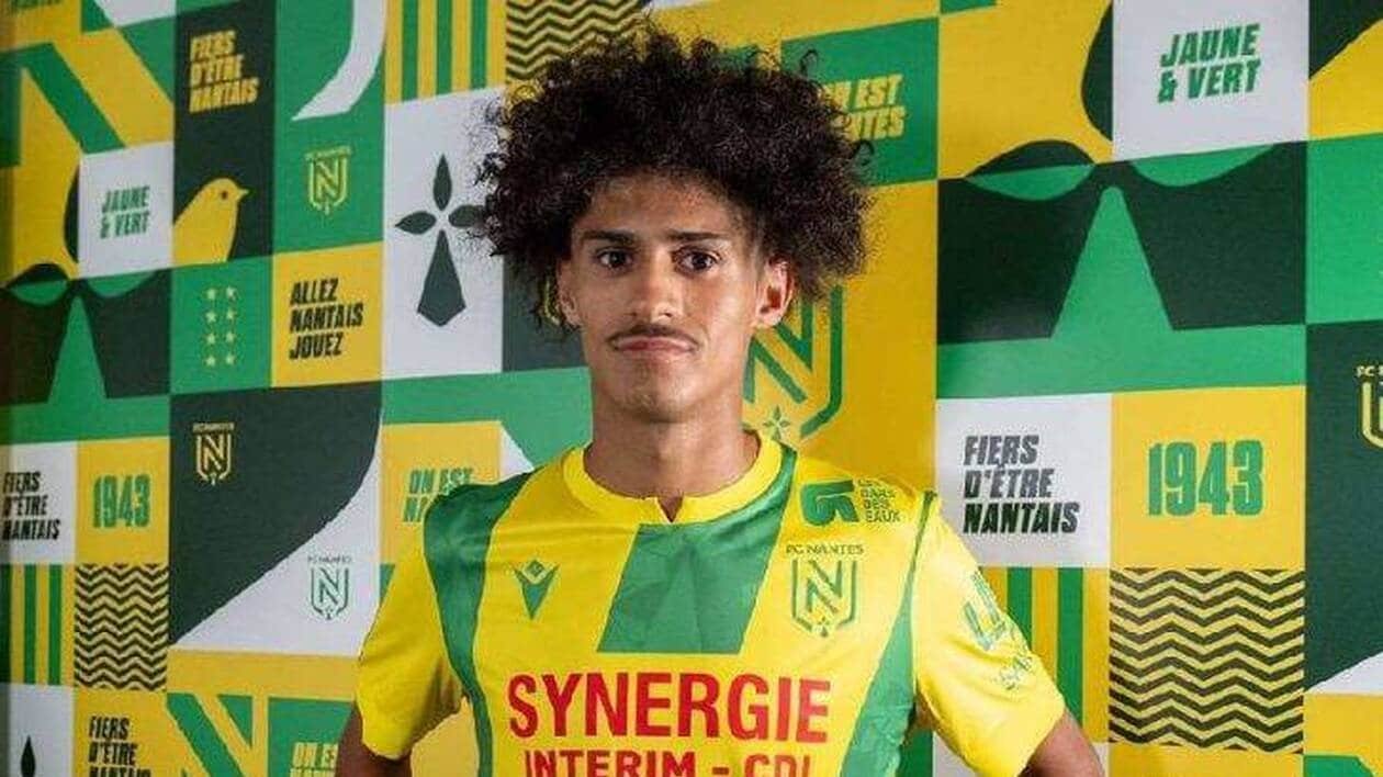 Young footballer in FC Nantes yellow-green jersey posing in front of a green-yellow patchwork backdrop.
