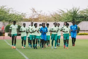 Soccer team in green uniforms jogging together on a grassy field during training, with two goalkeepers in blue among them. Soccer team in green uniforms jogging together on a grassy field during training, with two goalkeepers in blue among them.