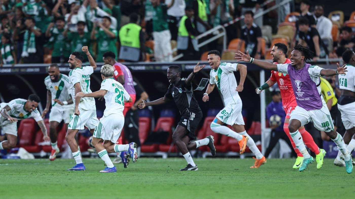Soccer players in white and green celebrate on the field as they run with arms raised after a goal