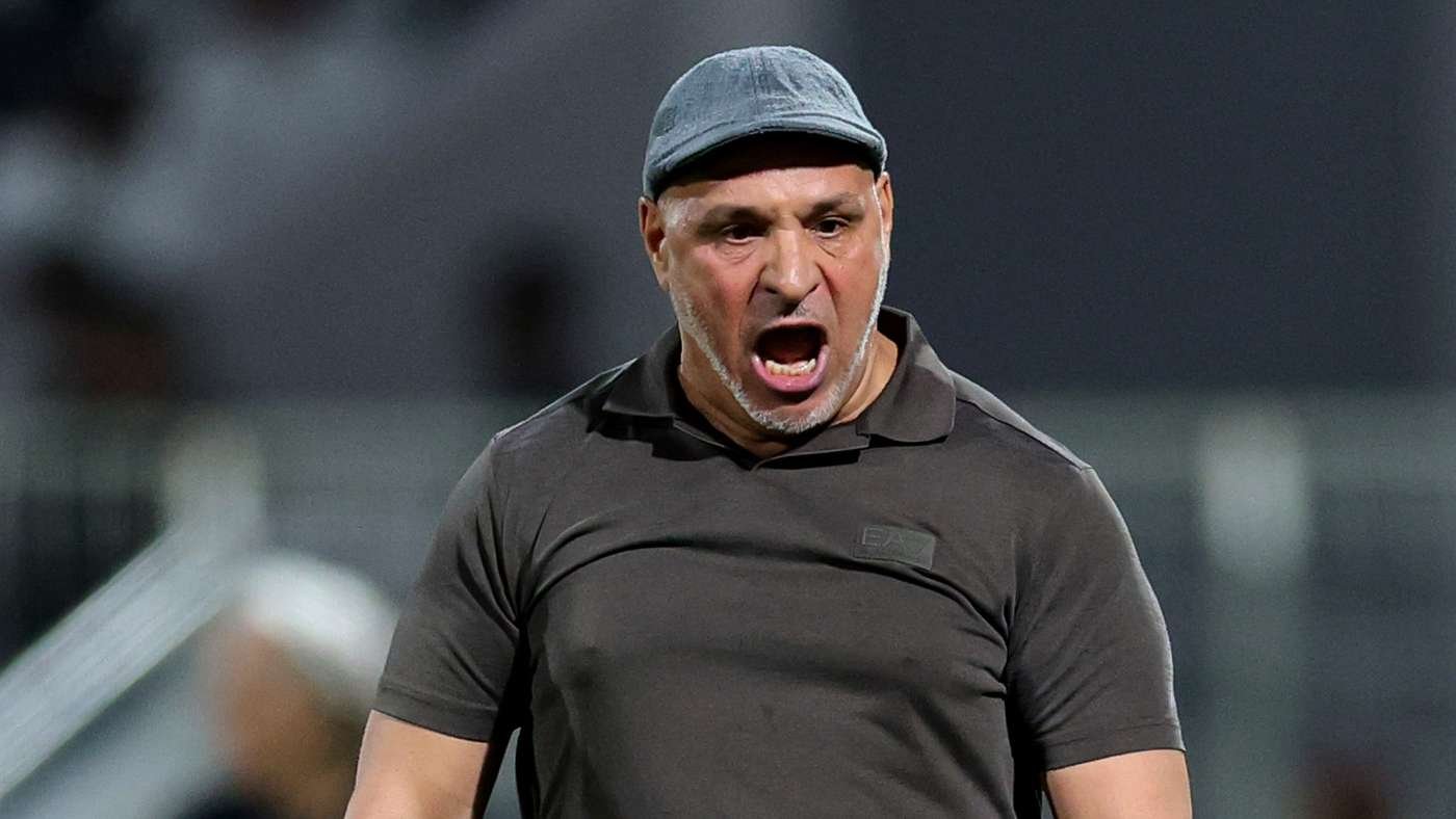 Athletic man in a dark polo and gray cap shouting during a game on the field
